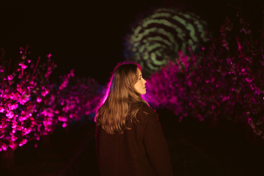 a girl walking under blossom by light